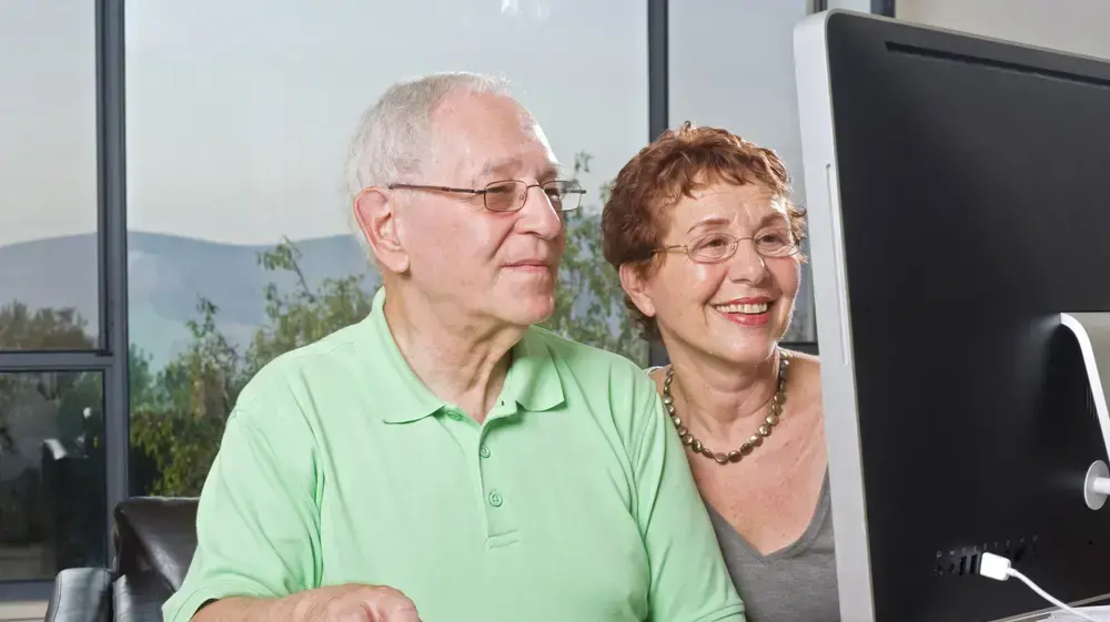 זוג מבוגרים יושבים מול מחשב