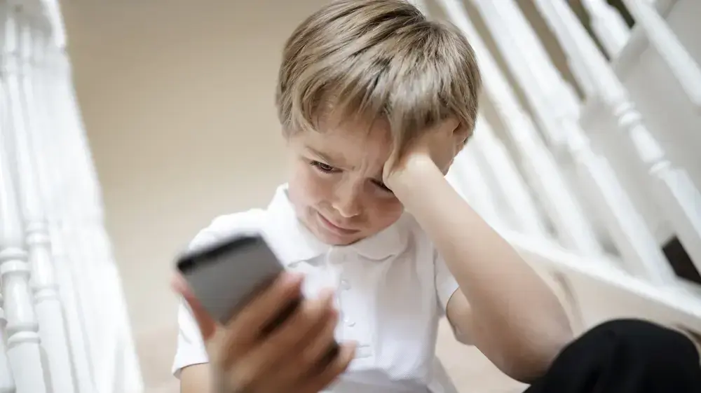 ילד גולש בסמארטפון ובוכה