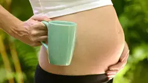 אישה בהריון מחזיקה כוס קפה אישה בהריון מחזיקה כוס קפה