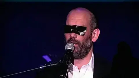 הזמר והיוצר יונתן רזאל מופיע בפני נשים עם מסנטייפ על עיניו