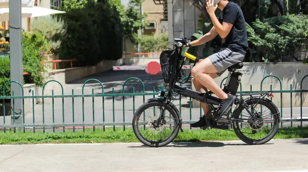 בחור רוכב על אופניים חשמליים בשדרות רוטשילד, תל אביב