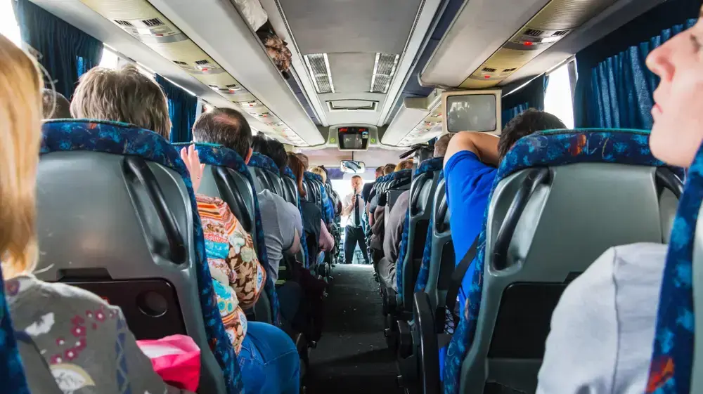 מדריך תיירים מסביר לקבוצת מטיילים במהלך נסיעה באוטובוס
