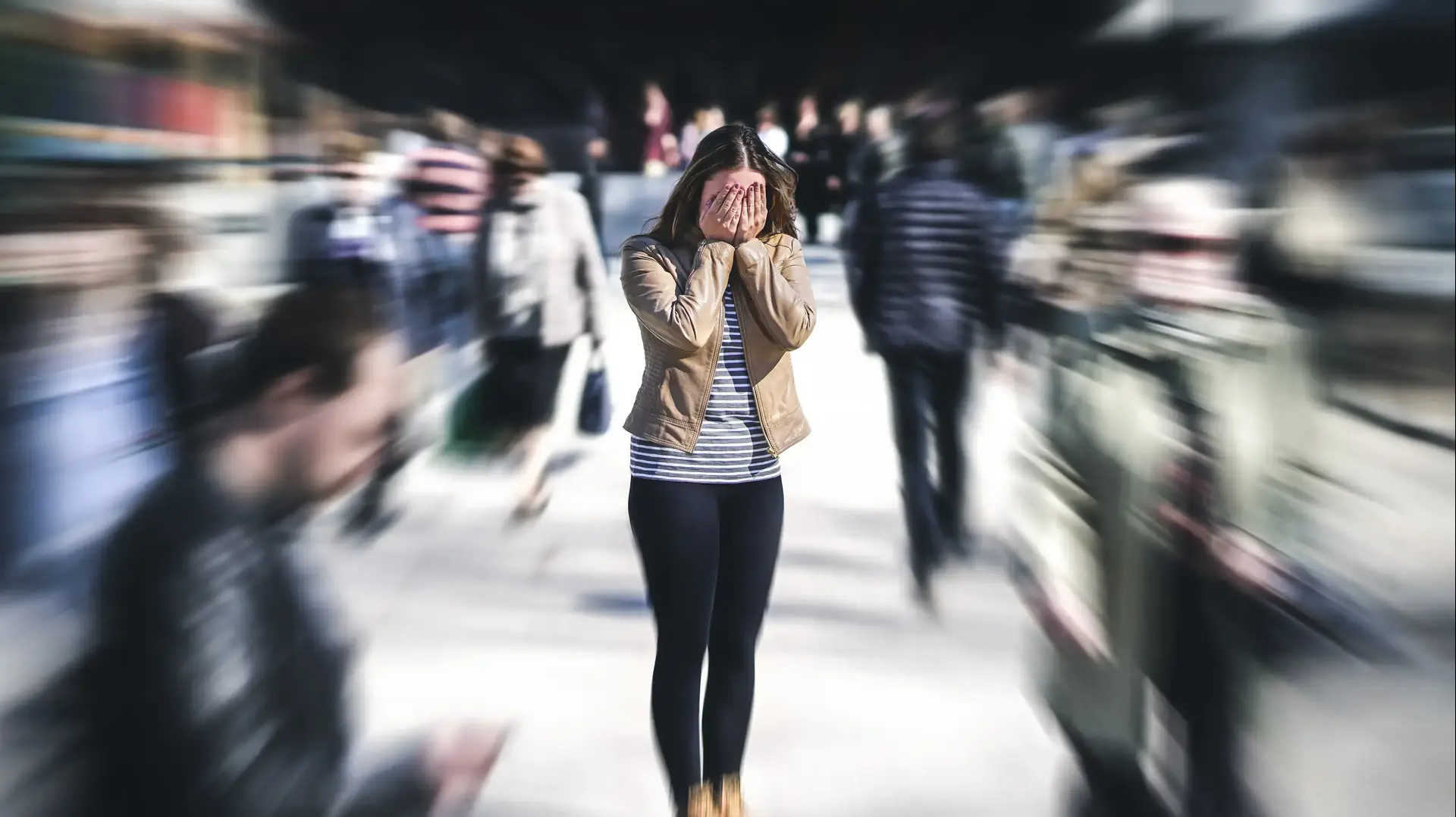 אישה ברחוב סואן מכסה את הפנים בידיים