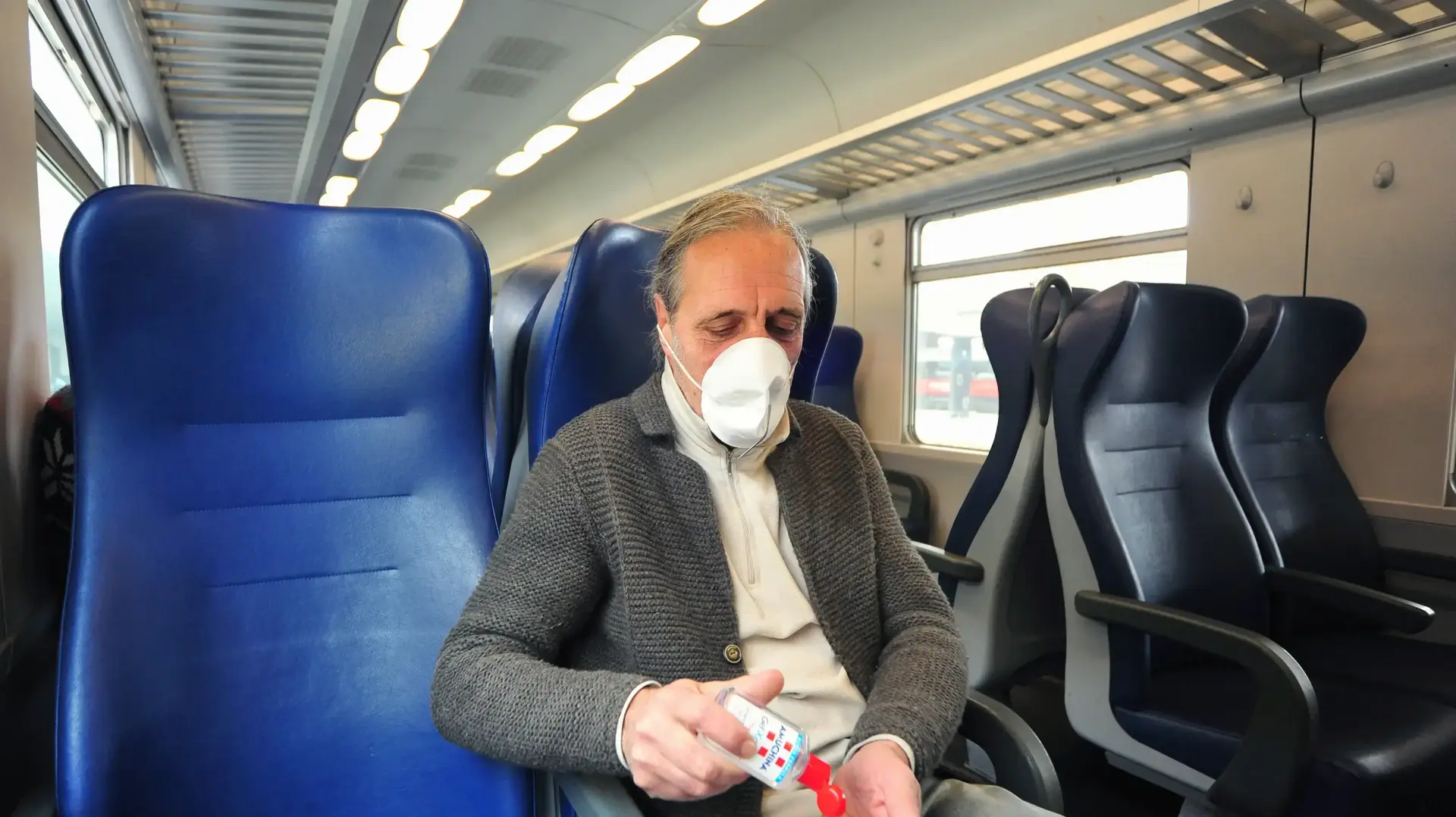 נוסע רכבת בפירנצה, איטליה, עם מסיכה ומחטא ידיים לאחר הטלת הסגר בצפון איטליה בעקבות הקורונה, 7 מרץ 2020