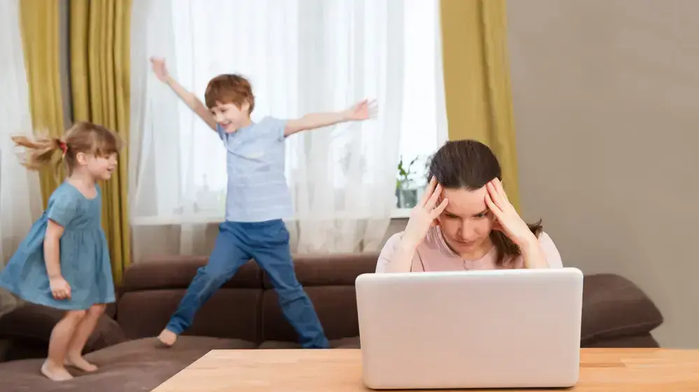 אישה מנסה לעבוד מהבית בזמן שהילדים שלה משתוללים בבית