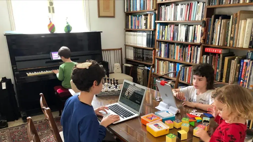 ילדים לומדים מרחוק מהבית מול מחשב