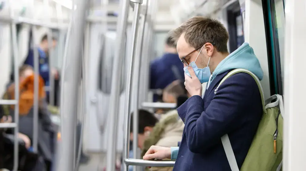 אדם עם מסיכה משתעל ברכבת התחתית
