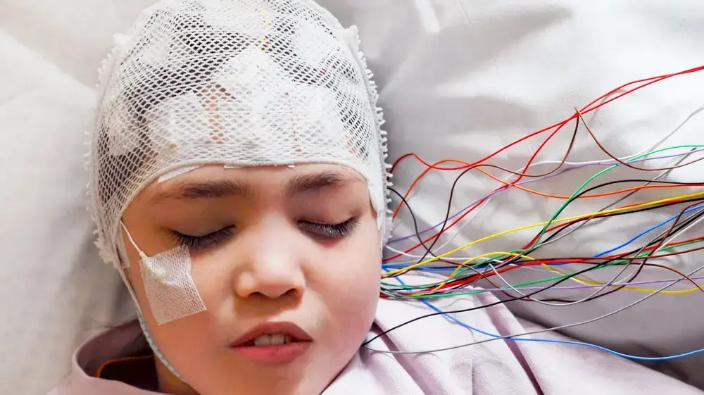 ילדה מחוברת למכשיר EEG שמנטר את פעילות המוח