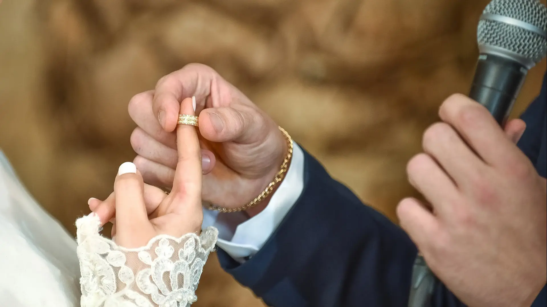 חתן מניח טבעת נישואין על אצבע של כלה