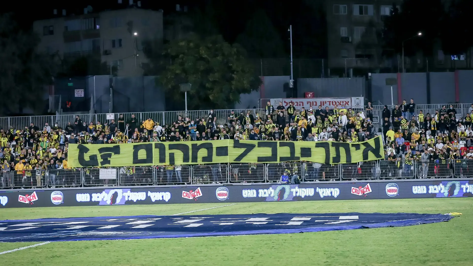 שלט של ארגון "לה פמיליה" במשחק של בית"ר ירושלים בנוף הגליל