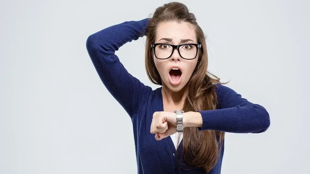 אישה מאחרת מביטה בשעון בתדהמה אישה מאחרת מביטה בשעון בתדהמה