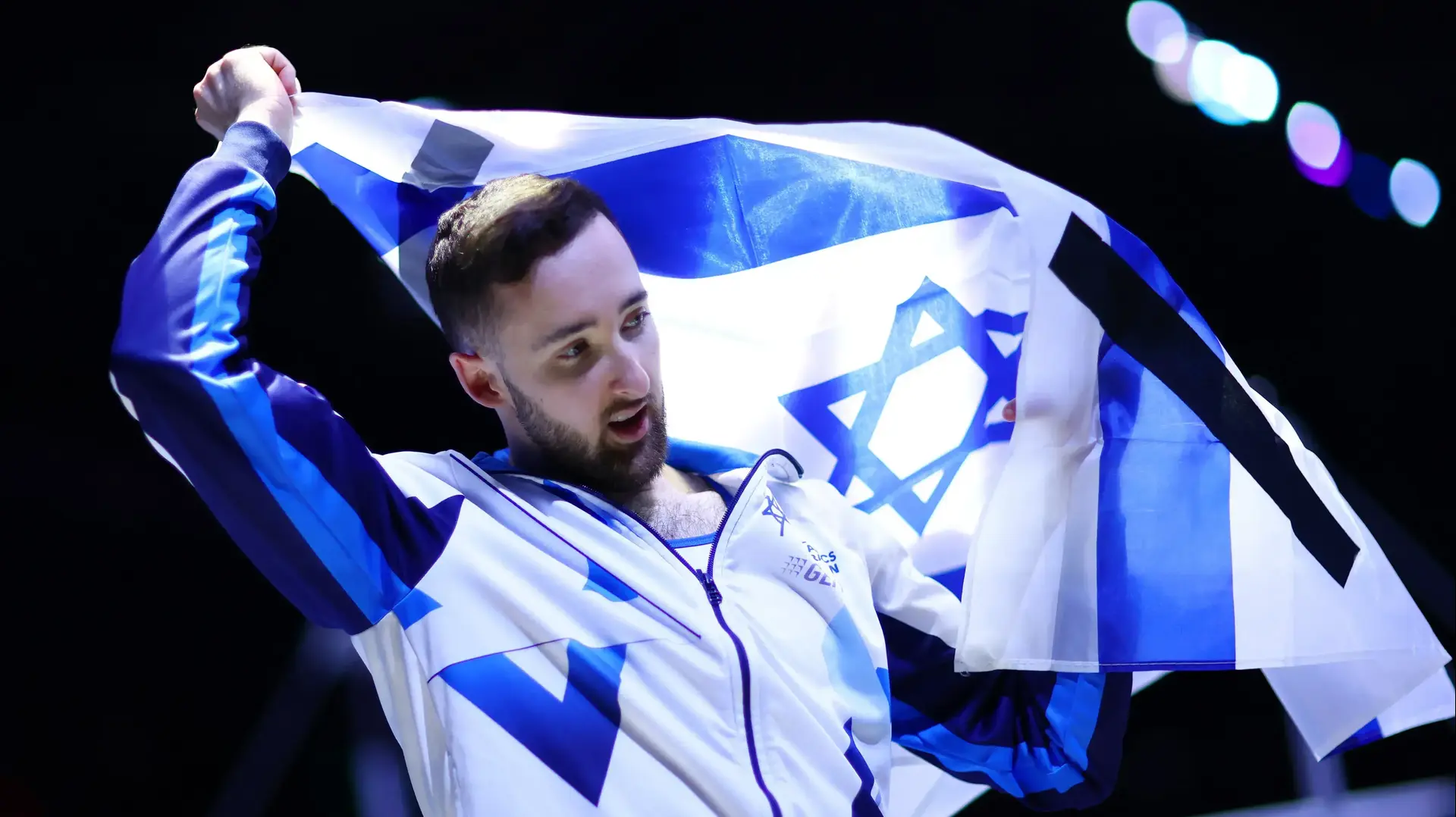 ארטיום דולגופיאט עם סרטים שחורים על דגל ישראל אחרי הזכייה שלו במדליית הזהב על תרגיל הקרקע באליפות העולם בהתעמלות