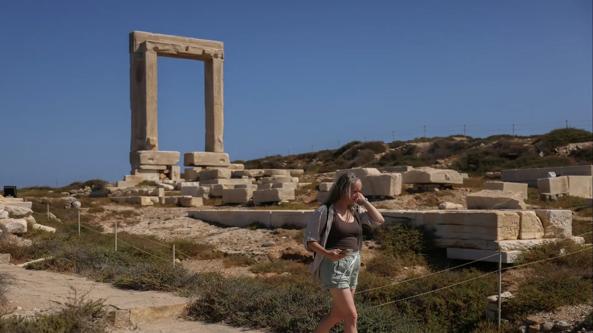 תיירת באתר המקדש הגדול של אפולו באי נקסוס ביוון, יולי 2024