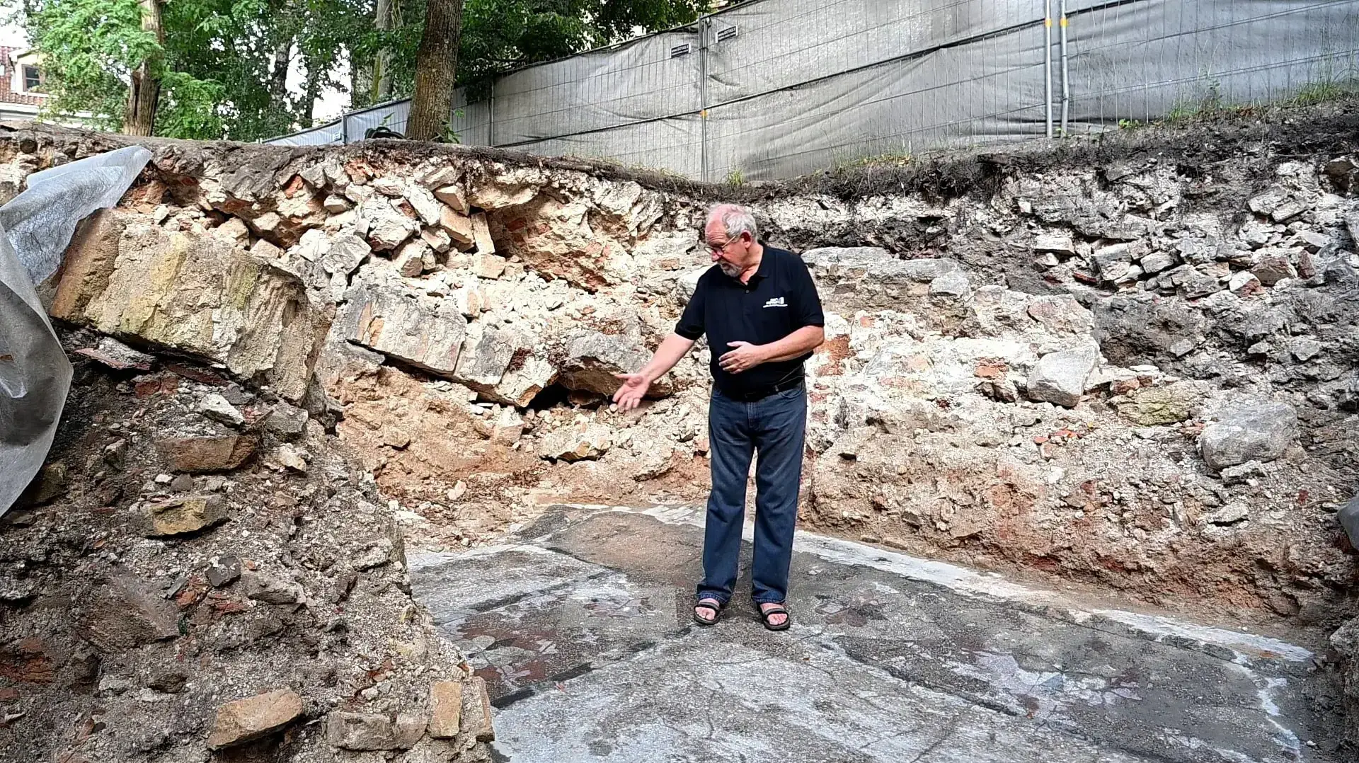ד"ר ג'ון זליגמן מרשות העתיקות מצביע על עיטור פרח שנחשף ברצפת בית הכנסת הגדול של וילנה