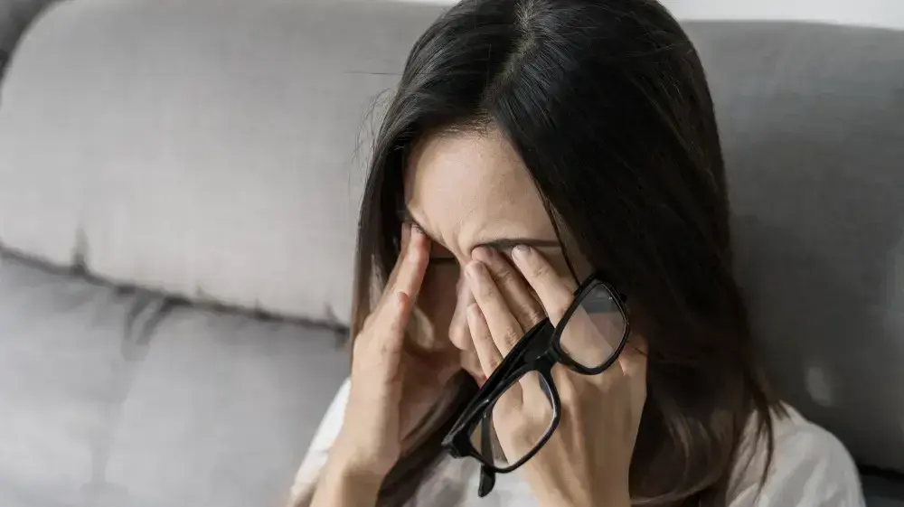 אישה משפשפת עיניים ומחזיקה משקפיים אישה משפשפת עיניים ומחזיקה משקפיים