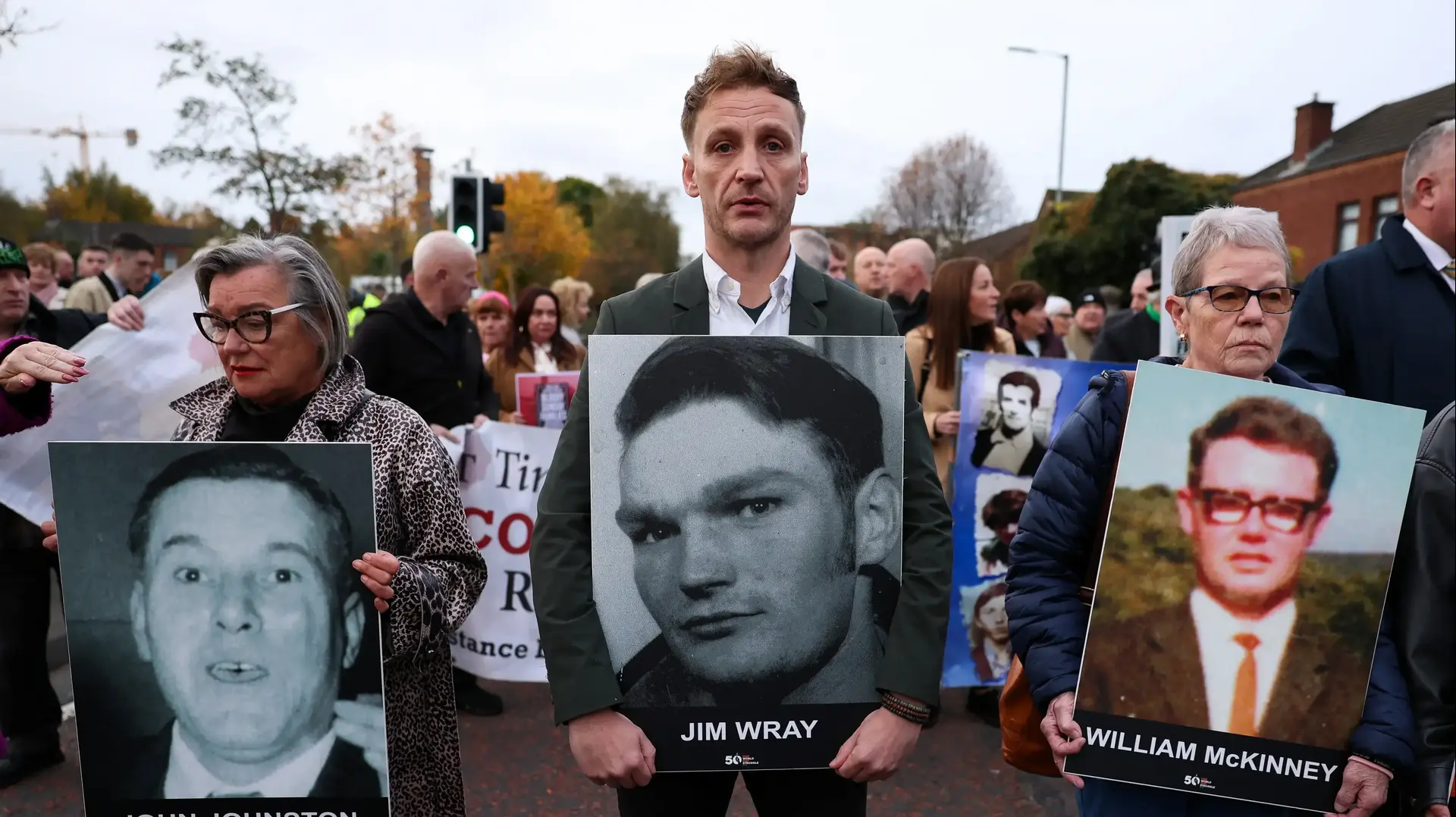 קרובי משפחה של קורבנות "בלאדי סאנדיי" אוחזים בתמונותיהם מחוץ לבית משפט בבלפסט, צפון אירלנד, 23 באוקטובר 2025