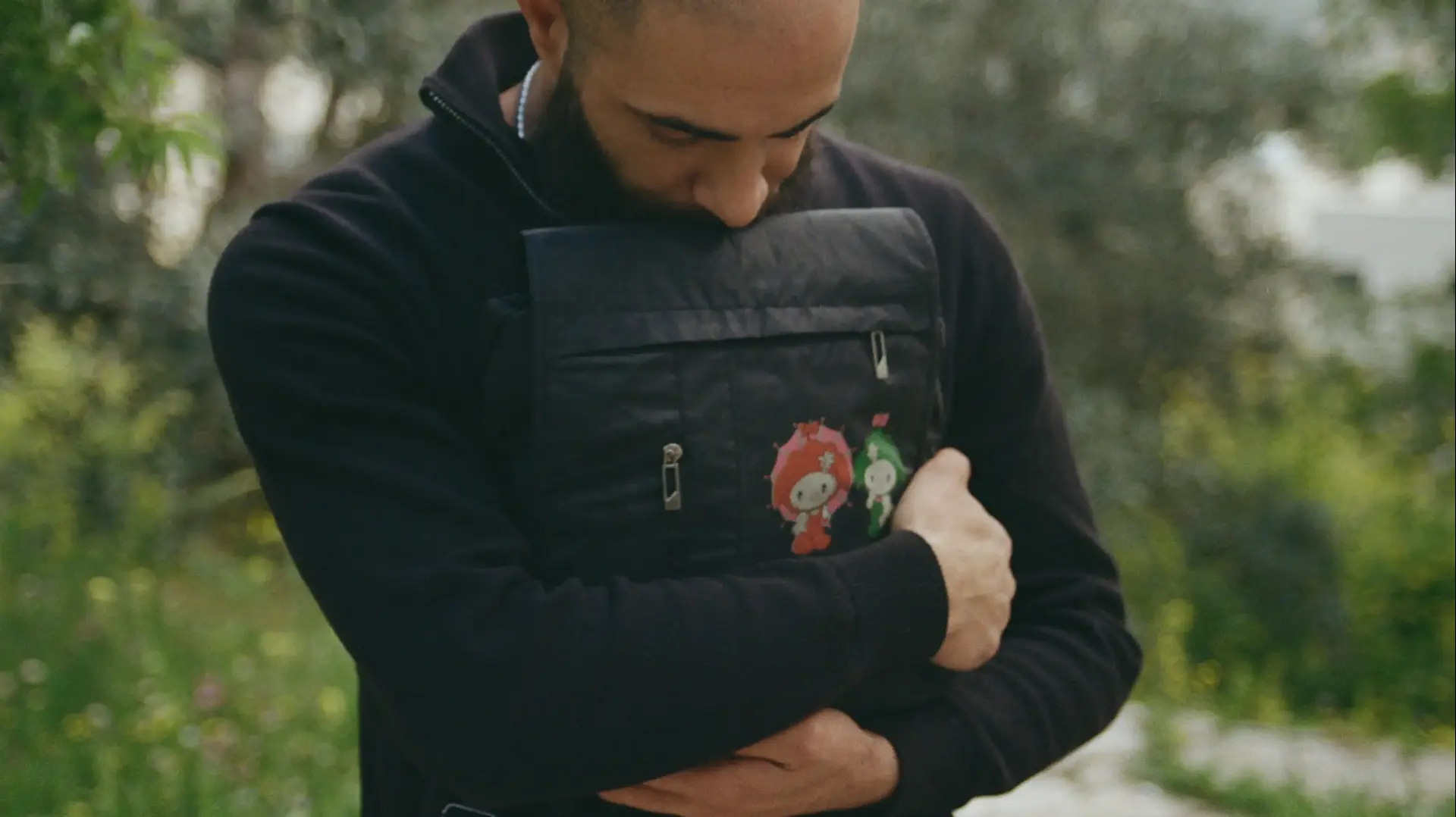 עראב עראמין עם תיק בית ספר של אחותו עביר שאיבד כשהייתה בת עשר ב-2007. צילום מתוך התערוכה "חפץ לב" הכוללת צילומים של ישראלים ופלסטינים שכולים המציגים פריטים יומיומיים שהיו שייכים ליקיריהם שנהרגו