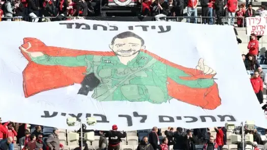 אוהדי הפועל ירושלים עם דגל לכבוד הלוחם הפצוע עידו נחמד