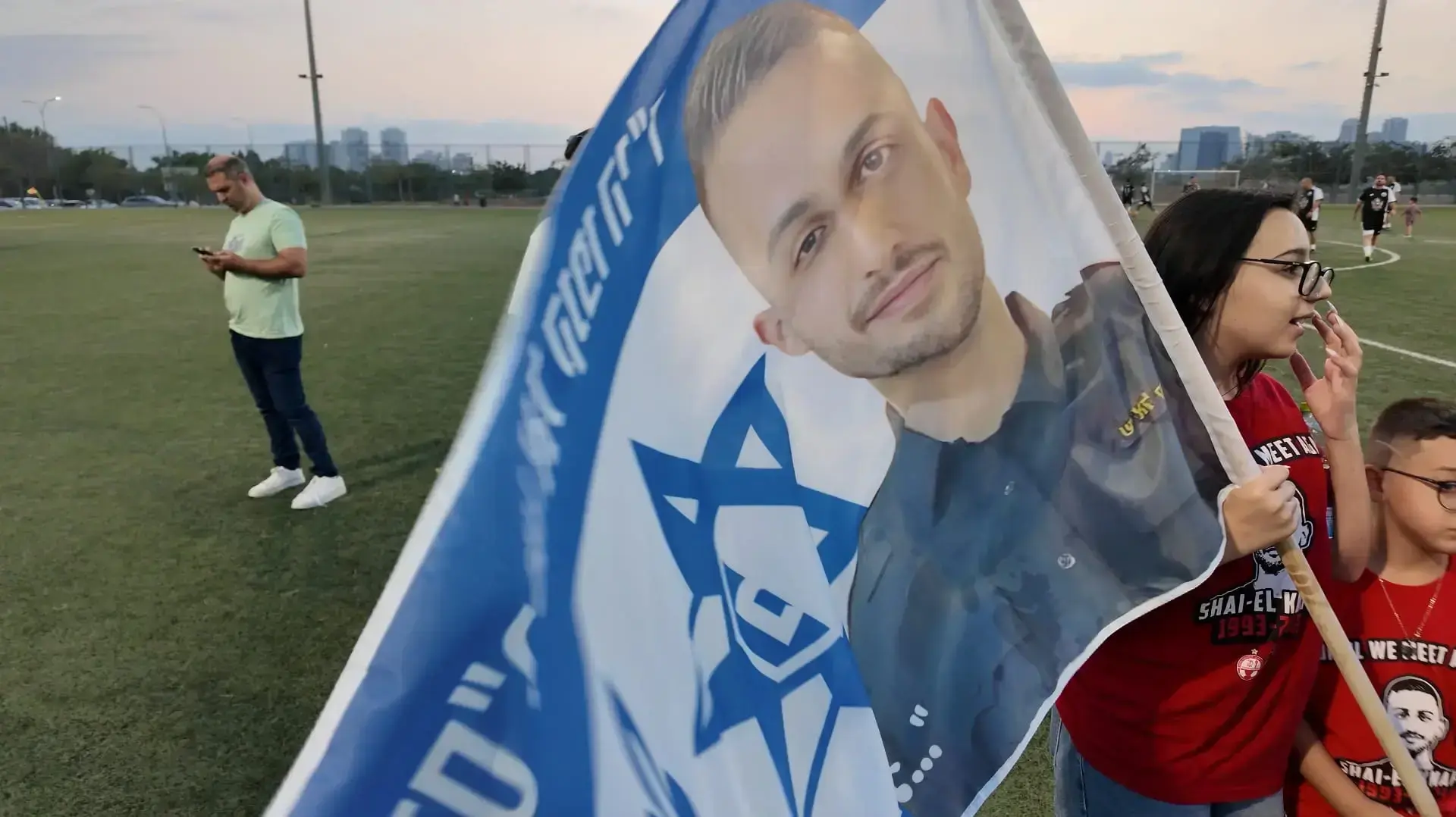 דגל עם תמונתו של שי-אל קנפו במשחק הכדורגל לזכרו