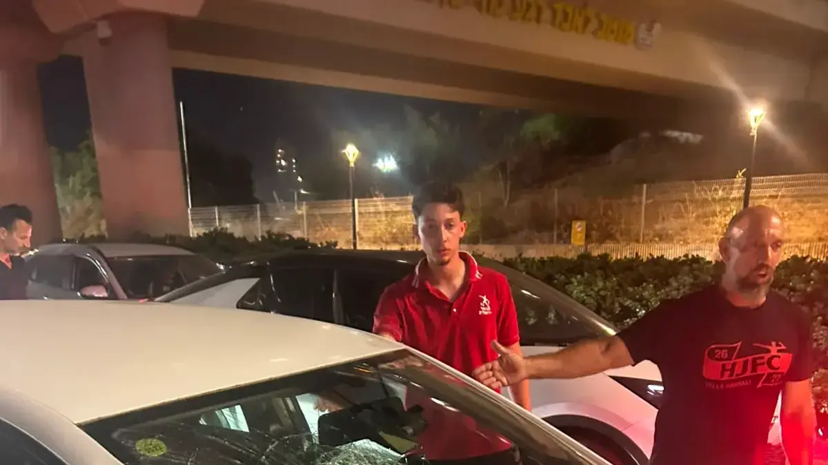 אוהדי הפועל ירושלים לצד רכב ששמשתו נופצה