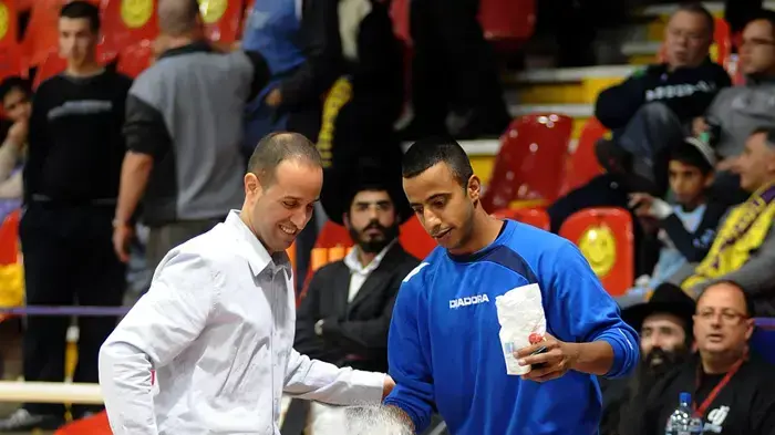עמיר עוזי מאמן הפועל חולון (שמאל) עם אוהד הקבוצה מנסים להסיר את המזל הרע