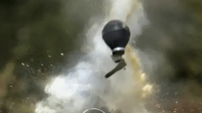 שוטר משמר הגבול יורה רימון גז מדמיע על מפגינים פלסטינים במהלך הפגנה נגד בניית גדר ההפרדה - יוני 2004