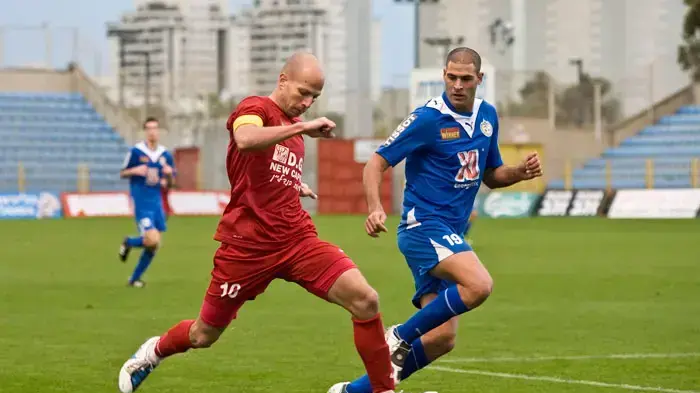 שחקן הפועל הרצליה יניב דוד (אדום) מול שחקן מכבי הרצליה, רגב וולק