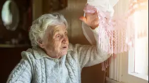 אישה זקנה מביטה בחלון