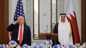 נשיא ארה"ב דונלד טראמפ מצדיע ליד אמיר קטאר תמים בן חמד א-ת'אני בזמן נגינת ההמנון בקטאר, 14 במאי 2025