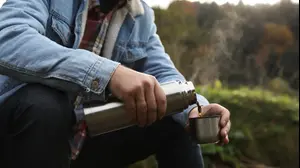 גבר שותה מתרמוס עם כוס תרמית