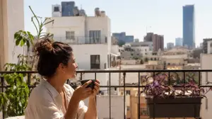 אישה שותה קפה במרפסת ביתה בתל אביב