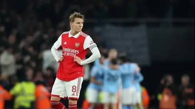 שחקן ארסנל מרטין אודגור מאוכזב, שחקני מנצ'סטר סיטי חוגגים ברקע. רויטרס