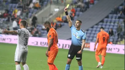 השופט ניב שטייף שולף כרטיס צהוב לעבר ארי מורה שחקן סקציה נס ציונה. שלומי גבאי