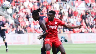 שחקן הפועל באר שבע יוג'ין אנסה לפני שחקן הפועל ירושלים אלוז' יאו. דני מרון