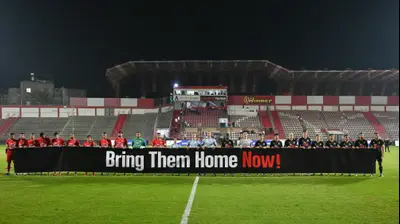 שחקני בני סכנין, מכבי נתניה, אוחזים בשלט שקורא להשבת החטופים. ברני ארדוב