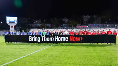 שחקני מ.ס. אשדוד, בני ריינה, מניפים את שלט החטופים. מאור אלקסלסי