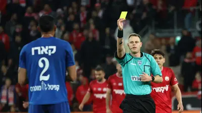 יגאל פריד שולף כרטיס צהוב לעבר אנדראס קארו שחקן מכבי פתח תקוה. דני מרון