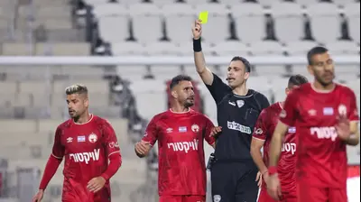 יואב מזרחי שופט כדורגל שולף כרטיס צהוב לעבר רותם חטואל שחקן הפועל באר שבע. מאור אלקסלסי