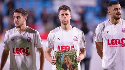 גיא מלמד שחקן הפועל חיפה עם שלט של החטופה רומי גונן. מאור אלקסלסי