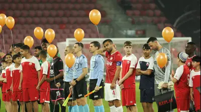 שחקני הפועל באר שבע עם בלונים כתומים לשחרור משפחת ביבס. קובי אליהו