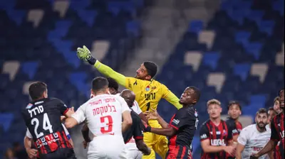 יואב ג'רפי שוער הפועל חיפה תופס אוויר וסופג שער של מתן בלטקסה שחקן הפועל באר שבע. מאור אלקסלסי