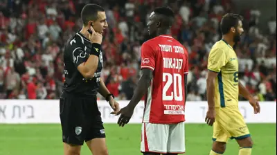 קינגס קאנגווה שחקן הפועל באר שבע עם השופט גל לוי. ברני ארדוב