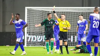 יוני קלז שופט כדורגל שולף כרטיס צהוב לעבר סקו בנגורה שחקן עירוני קרית שמונה. קובי אליהו