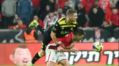 שחקן מכבי נתניה, יובל שדה, מבצע עבירה על שחקן הפועל באר שבע איגור זלאטנוביץ'. ברני ארדוב