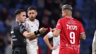 רותם חטואל שחקן הפועל חיפה עם השופט יובל שטיין, ביניהם מארון גנטוס שחקן בני סכנין. מאור אלקסלסי