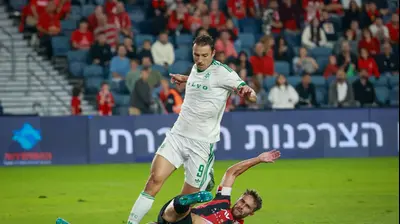 שחקן הפועל ירושלים, עומר אגבדיש עוצר את חלוץ מכבי חיפה אנדריה נובאקוביץ'. קובי אליהו